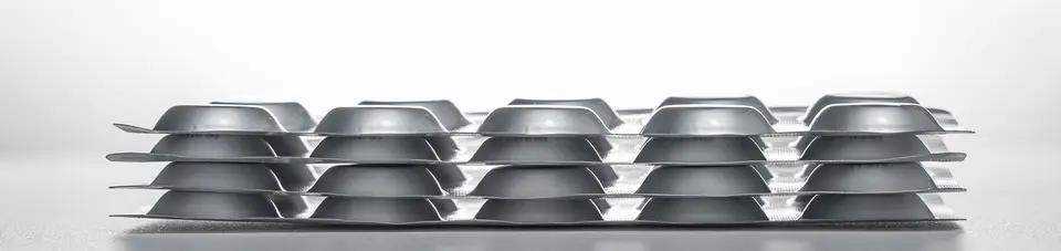 Rows of blister packs sealed with aluminium foil, seen from the side