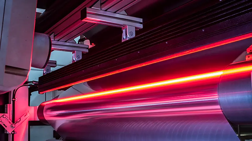 A line of the plant lit in red, with the aluminium web running on the rollers